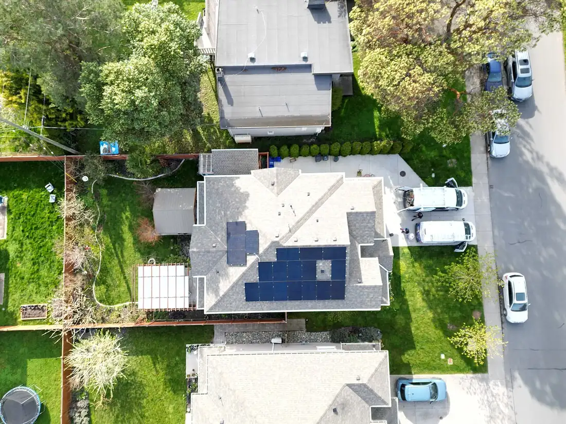 Aerial view of a house roof with solar modules in separate groups placed around vents and roof edges
