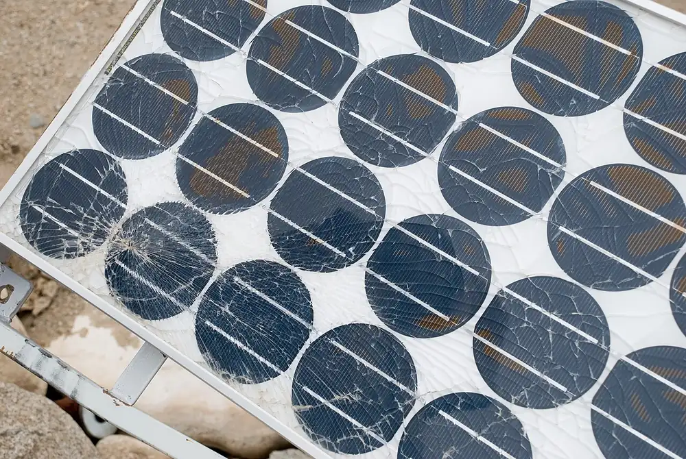 Close-up of an old solar module with cracked cells and brown discoloured patches under the glass