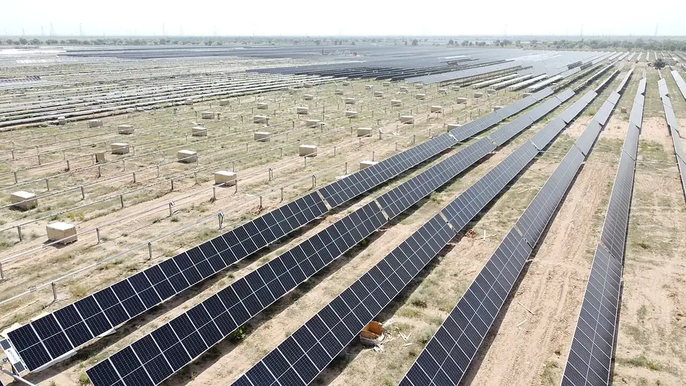 Aerial view of long rows of solar modules on dry, sandy ground in the Bhadla solar park in Rajasthan, India