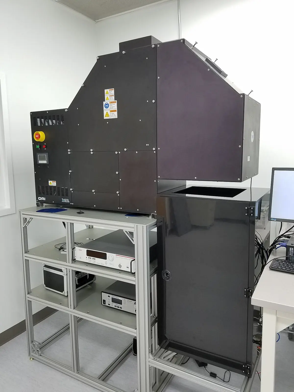 Laboratory solar simulator, a large dark enclosure on a metal rack with measurement instruments underneath